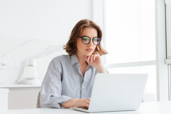 charming-businesswoman-glasses-striped-shirt-working-with-laptop-computer-while-siting-home_171337-13027